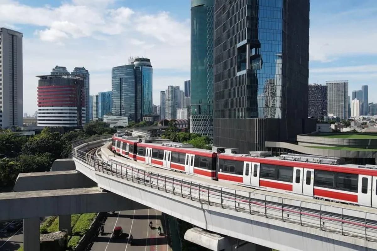 Rangkaian LRT Jabodebek melintasi jalur layang di antara gedung bertingkat